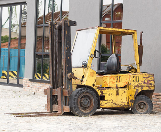 An empty forklift sitting next to a building
