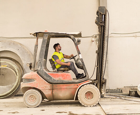 A man driving by in a forklift