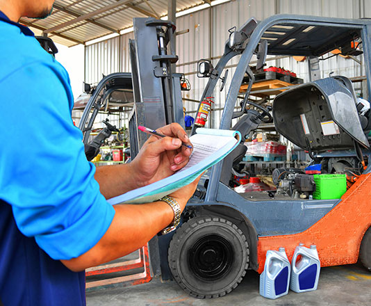 mechanic-looking-over-forklift-and-clipboard-writing